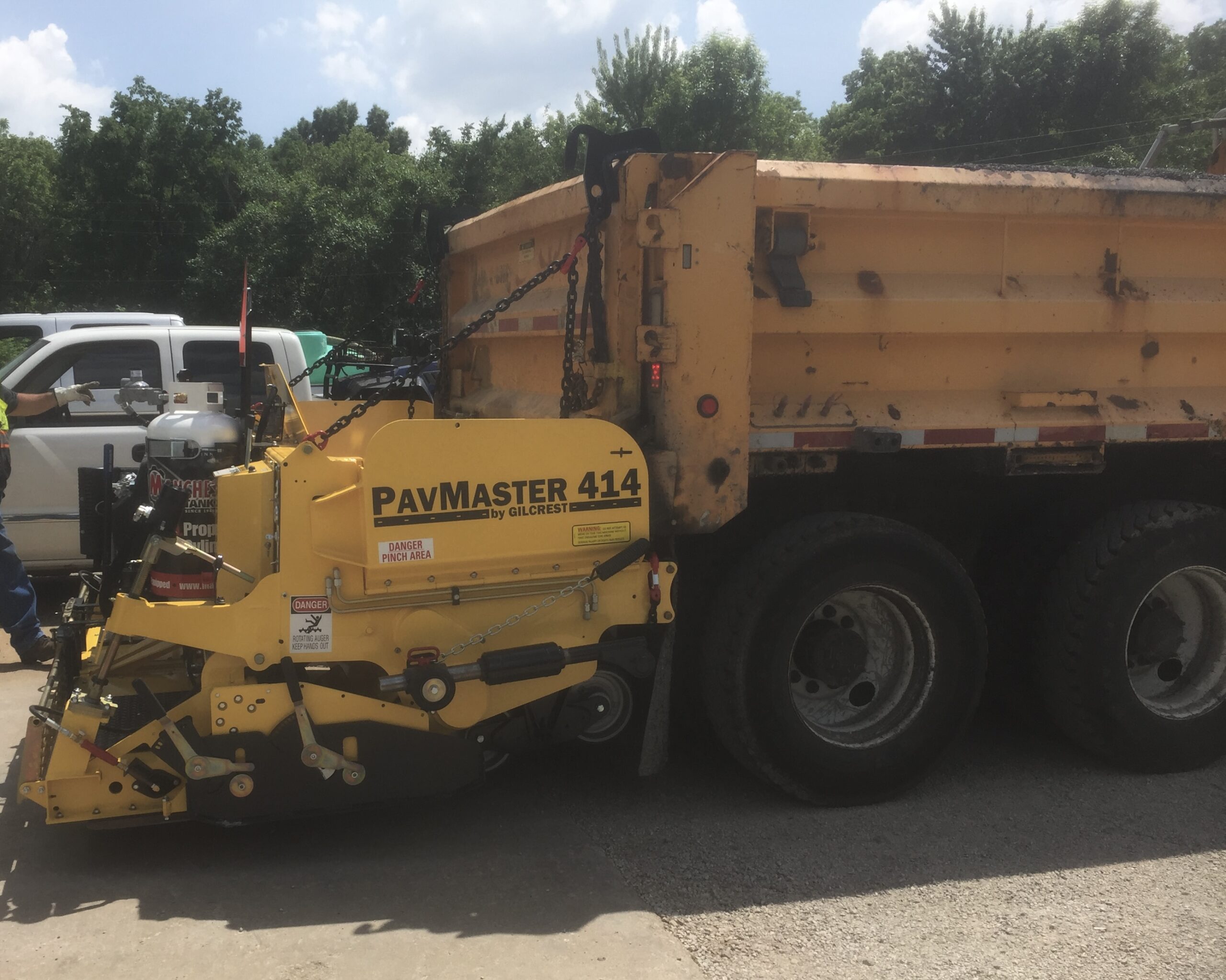 A yellow dump truck parked in a parking lot, showcasing its vibrant color against the asphalt surface.