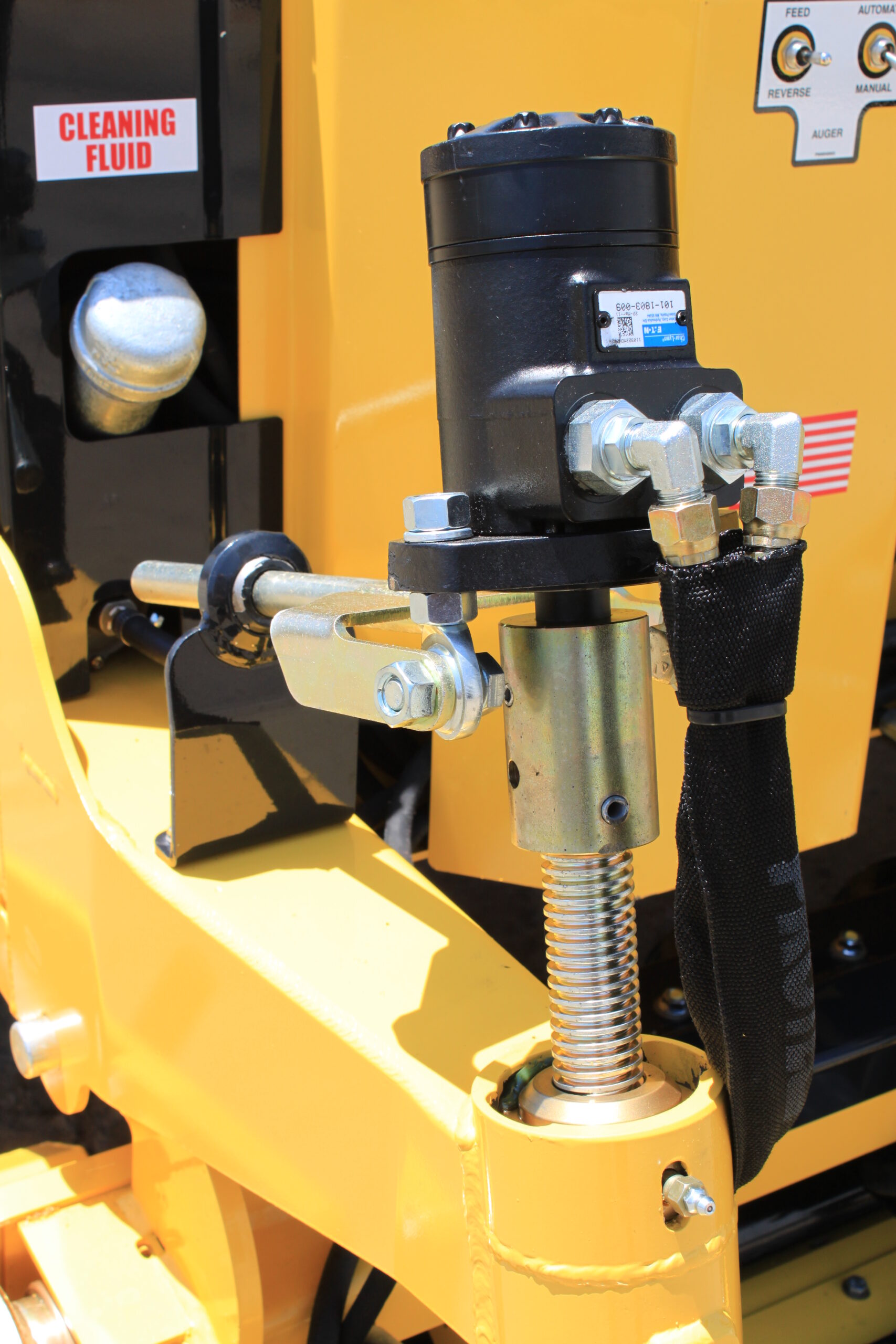 A close-up view of a yellow machine featuring a prominent hydraulic arm, showcasing its intricate design and functionality.