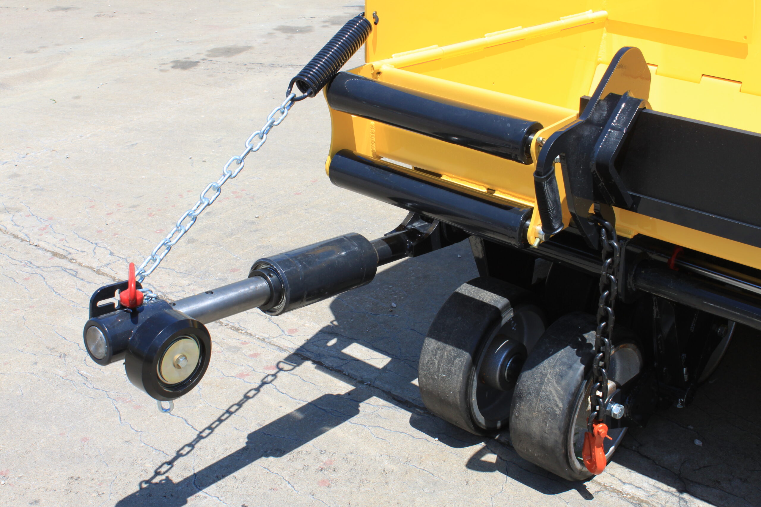A bright yellow dump truck stands stationary in a parking lot, highlighting its robust design and color.