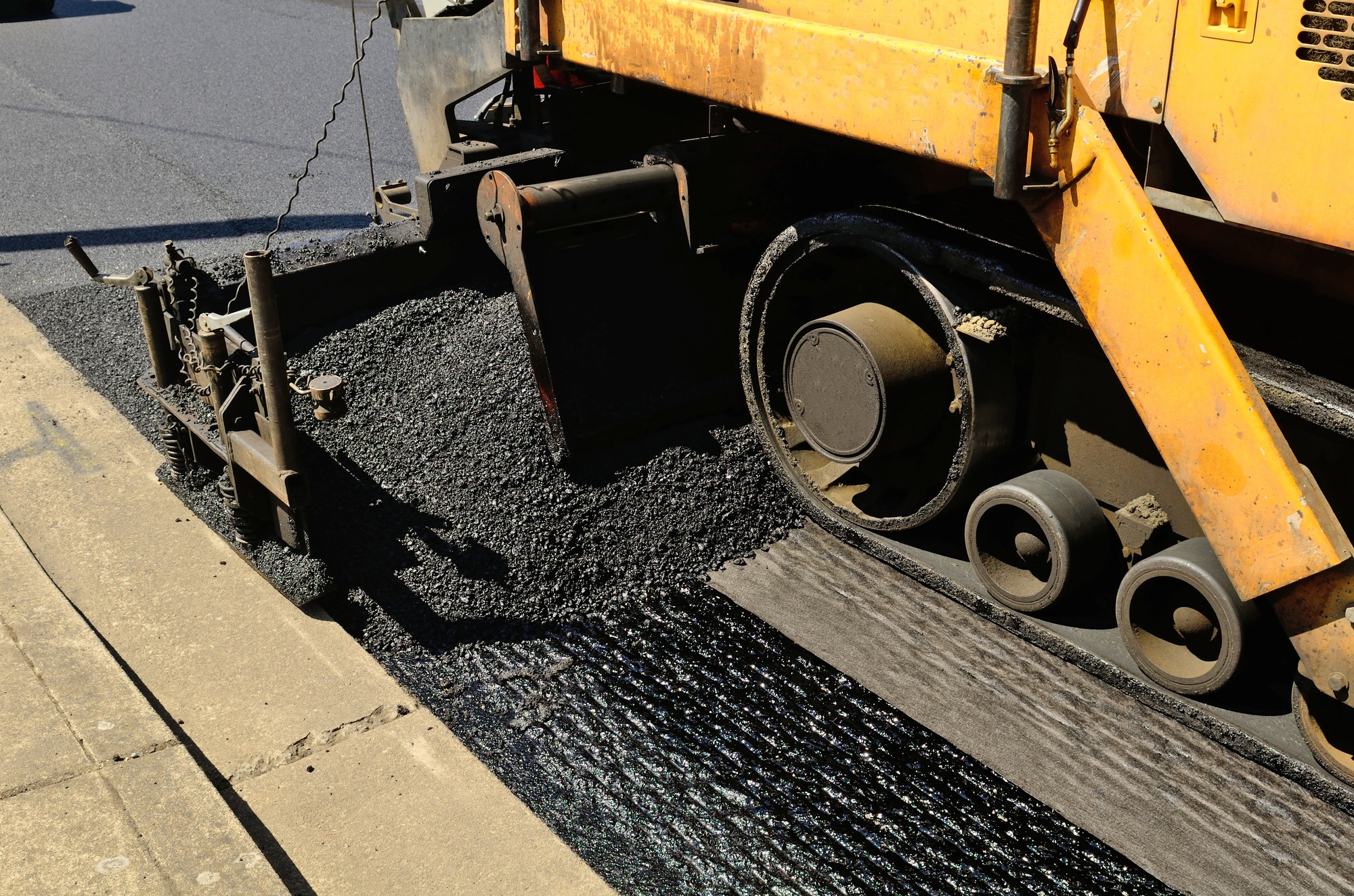 A paver finisher asphalt finisher or paving machine placing a layer of asphalt during a repaving construction project